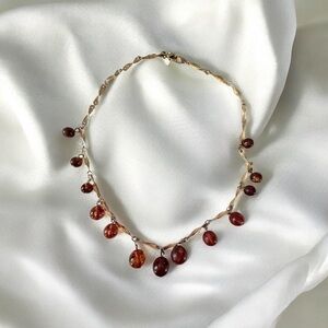 necklace with a twisted gold-tone chain and dangling cherry-amber  beads.